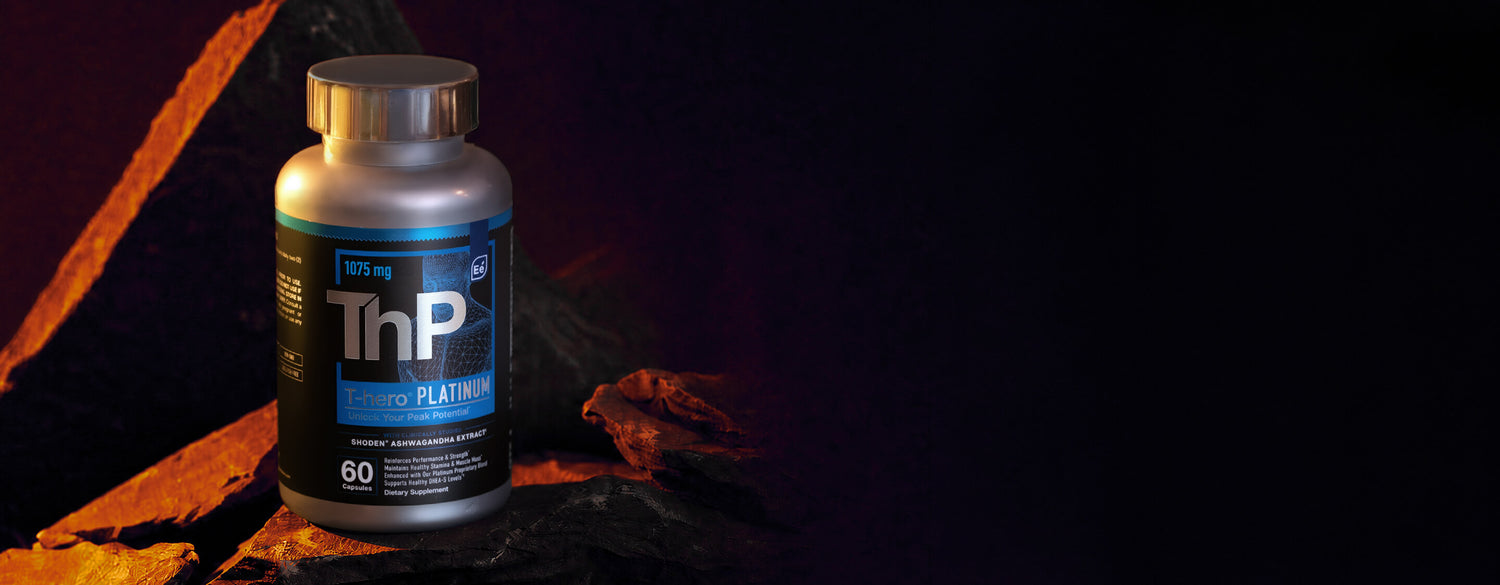 A bottle of T-hero Platinum dietary supplement on granite, set against a dark background with warm, dramatic lighting.